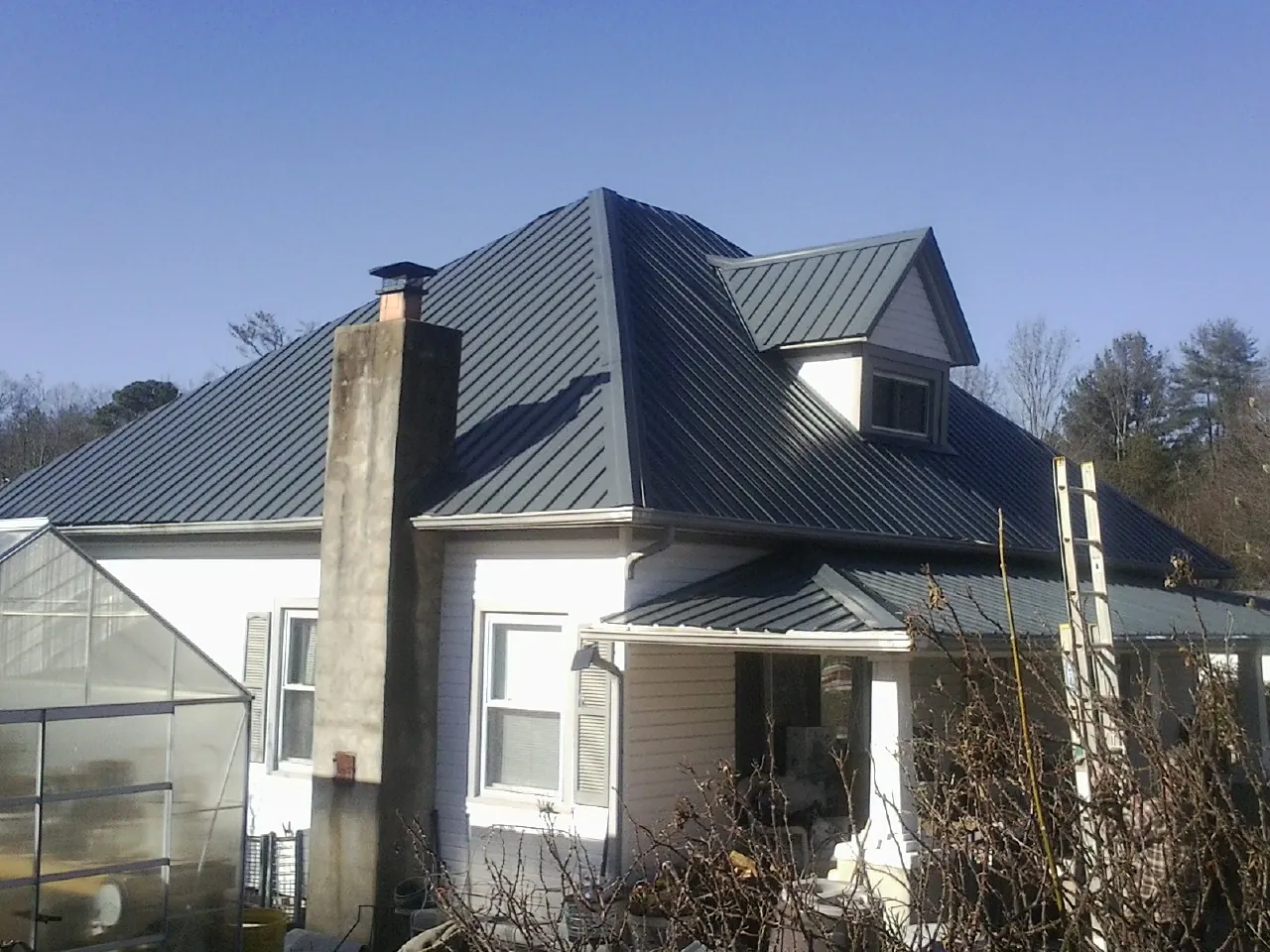 Dark blue standing seam metal roof on a white farmhouse with dormer — Slate & Tile Roof Repair by Roofing Brothers in Mount Vernon