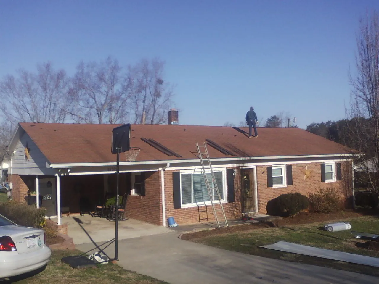 Roofer stripping a shingle roof on a brick ranch before metal panels in Mount Vernon